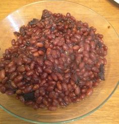 a glass bowl filled with red beans on top of a wooden table