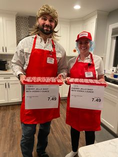 two people in red aprons holding up signs