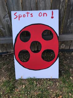 a sign that says spots on in front of a wooden fence with grass and dirt around it