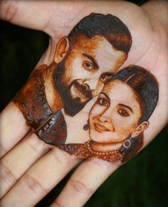 a person's hand painted with an image of two people on it and one is holding