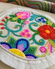 a white plate topped with lots of colorful bead work on top of a table