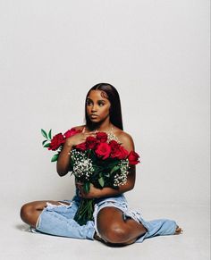 a woman sitting on the floor with roses in her hands and looking at the camera