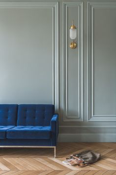 a blue couch sitting on top of a hard wood floor next to a white wall