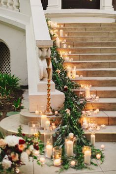 candles are lined up on the stairs with greenery