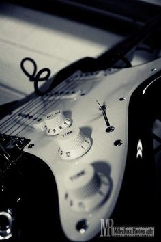 a white electric guitar laying on top of a table next to a pair of scissors