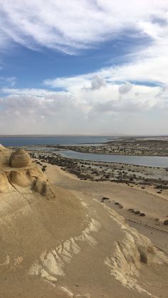 the desert is covered in sand and water under a blue sky with clouds above it