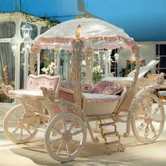 a white carriage with pink and gold trimmings in a room filled with furniture