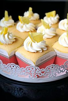 there are many cupcakes with white frosting and lemon slices on the top