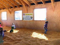 three children are playing in the sand inside a wooden structure that is being used as an indoor play area