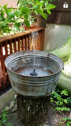 an old metal bucket filled with water on top of a wooden deck next to a tree