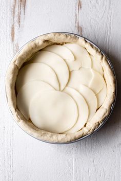 an uncooked pie crust in a metal pan on a white wooden table top