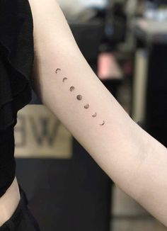 a woman's arm with the phases of planets tattooed on her left arm, in black and white