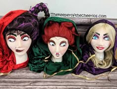 three creepy dolls sitting on top of a wooden bench with their faces painted red, green and purple