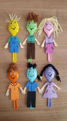 paper dolls made to look like people with different hair colors and body shapes, standing on a wooden surface