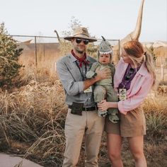 a man and woman standing next to each other in front of an animal statue with a dinosaur on it's head