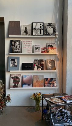 a book shelf filled with books next to a wall covered in posters and pictures on it