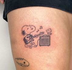 a person with a tattoo on their leg playing the guitar and singing into a radio