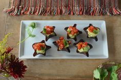 small appetizers are arranged on a white plate with garnishes and greens