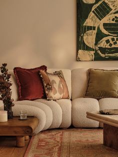 a living room filled with lots of furniture next to a painting on the wall above a coffee table