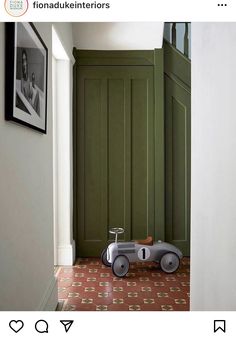 a toy car is sitting on the floor in front of a green paneled door