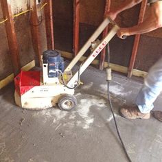 a man using a floor grinder to cut up the concrete in his home under construction