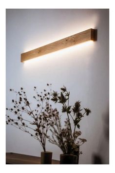 a light that is on the side of a wall next to some vases with flowers