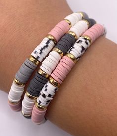 four bracelets with different colors and designs on each one hand, all stacked together