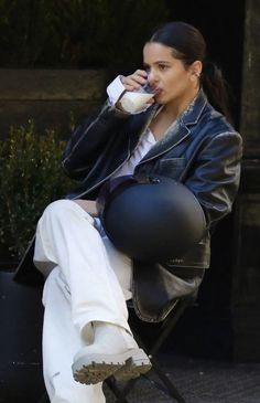 a woman sitting in a chair drinking from a cup