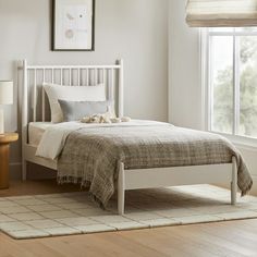 a white bed sitting in a bedroom next to a window