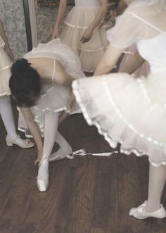 a group of young women standing next to each other on top of a wooden floor