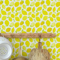 yellow lemons are hanging on the wall next to wooden utensils and a cutting board