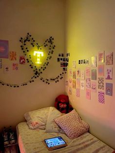 a bed room with a laptop on top of it next to a wall covered in pictures