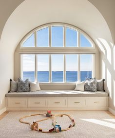 a window seat with toys on the floor in front of it and an arched window