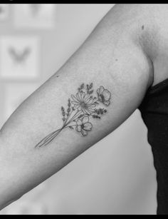 a black and white photo of a woman's arm with flowers tattooed on it