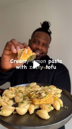 a man holding up a piece of food on top of a metal tray in front of him