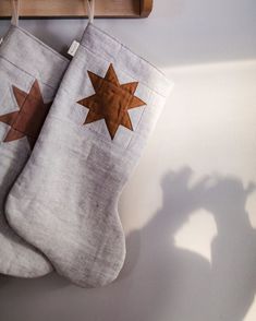 two christmas stockings hanging from a wooden rack on the wall next to a shadow of a person