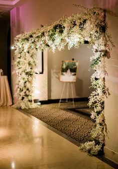 an archway decorated with white flowers and greenery