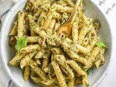 a white bowl filled with pasta covered in pesto