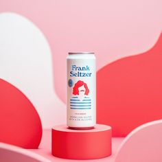 a can of frank seltzer sitting on top of a pink stand in front of a red and white background