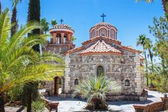 an old church surrounded by palm trees on a sunny day