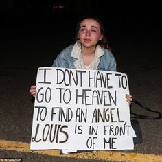 a woman holding a sign that says i don't have to go to heaven to find an angel louis is in front of me