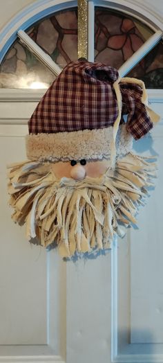 a door hanger with a face made out of cloth and wood shavings