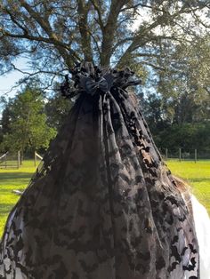 a woman is wearing a black dress and has a large bag on her head in the shape of a tree