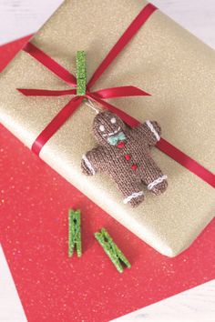 a brown teddy bear sitting on top of a white present box next to green letters