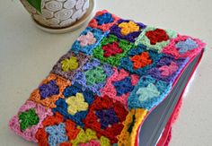 a crocheted book is sitting on a table next to a potted plant