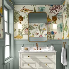 a bathroom with two sinks and a large mirror above the sink is decorated in tropical wallpaper