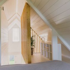 an attic bedroom with white walls and wood trim on the ceiling, along with a bed in the foreground