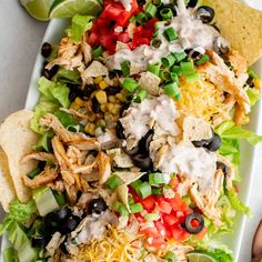 a salad with black olives, tomatoes, corn, cheese and tortilla chips