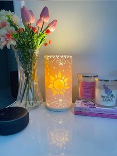 a table topped with a vase filled with flowers next to a candle and other items