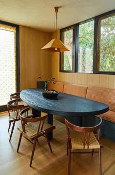 a dining room table with four chairs and a bowl of fruit on the center piece